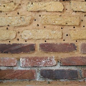 Ungebrannte Lehmziegel und Lehmputz mit L&ouml;chern